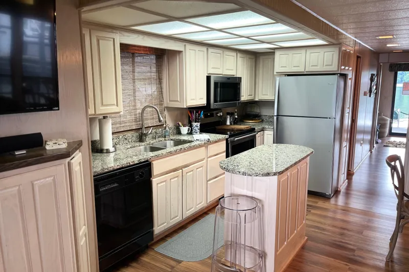Slide: The Image of Modern kitchen interior in a 1997 Lakeview 65x18 houseboat with granite countertops and wood flooring. - 6