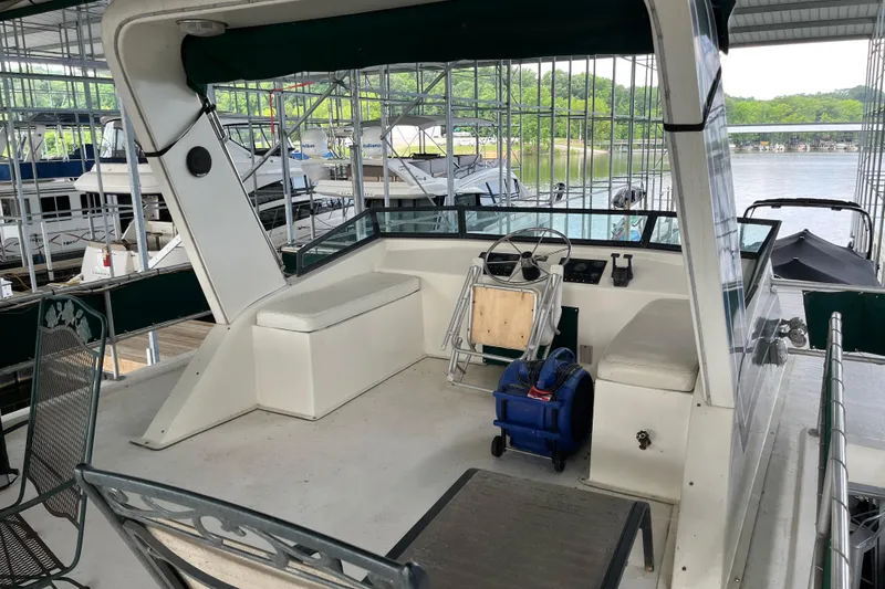 Slide: The Image of 1997 Lakeview 65x18 houseboat interior with steering wheel, seating, and docked boats in background. - 21