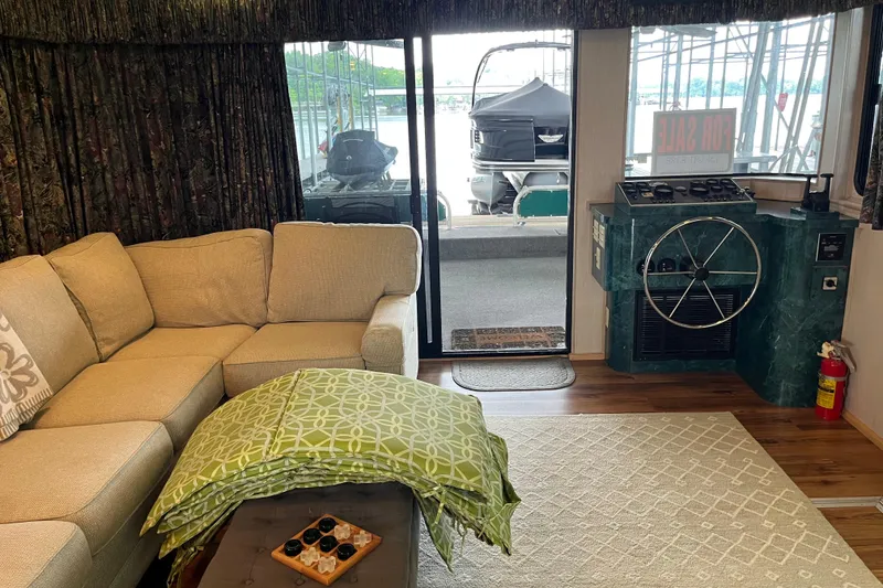 Slide: The Image of Cozy interior of a 1997 Lakeview 65x18 houseboat with a beige sofa and helm station. - 9
