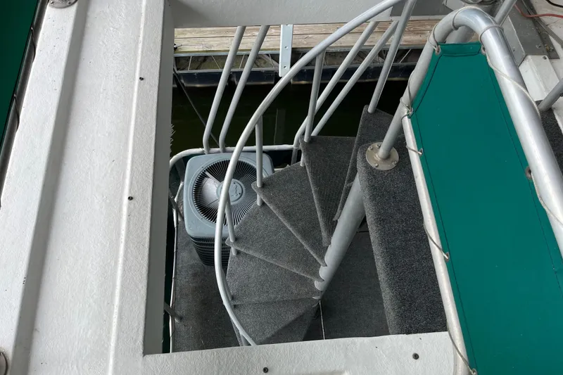 Slide: The Image of Spiral staircase on 1997 Lakeview 65x18 houseboat with green accents and dock view. - 26
