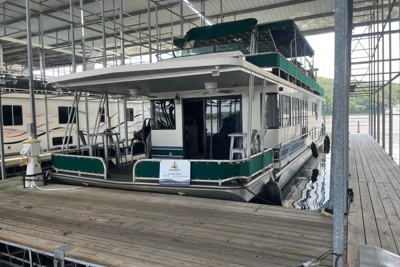 The Image of Houseboat docked in marina, Lakeview 65x18 model, 1997, with green accents and covered upper deck. - 1