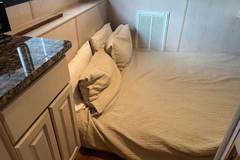 Slide: The Image of Cozy bedroom in 1997 Lakeview 65x18 houseboat with beige bedding and wooden cabinetry. - 15