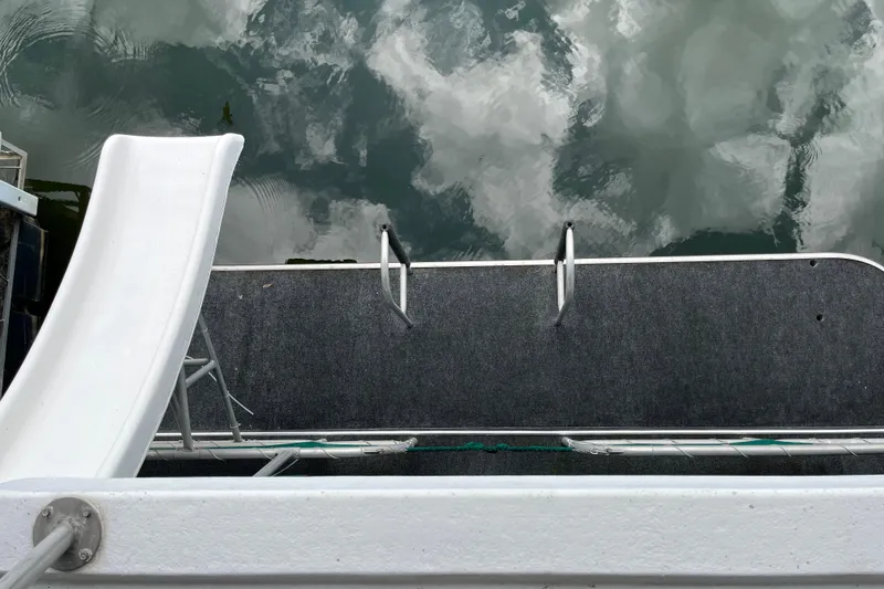 Slide: The Image of Houseboat deck with slide and ladder, Lakeview 65x18, 1997 model, reflecting cloudy sky. - 25