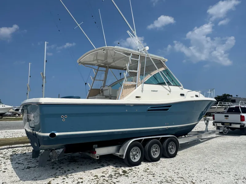 Slide: The Image of A 2002 Pursuit 3000 Express boat on a trailer in a gravel lot. - 4