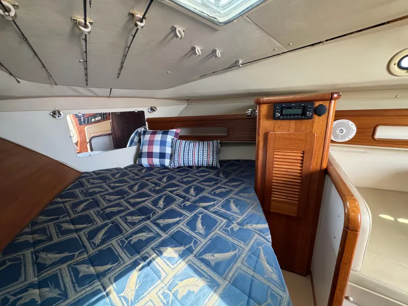 Slide: The Image of Interior of a 2002 Pursuit 3000 Express with a cozy bed and wooden accents. - 27
