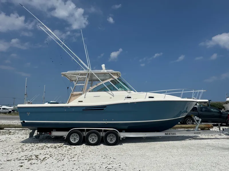 Slide: The Image of A 2002 Pursuit 3000 Express boat on a trailer in a gravel lot. - 5