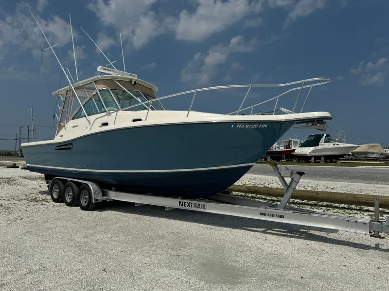 Slide: The Image of A 2002 Pursuit 3000 Express boat on a trailer in a gravel lot. - 6