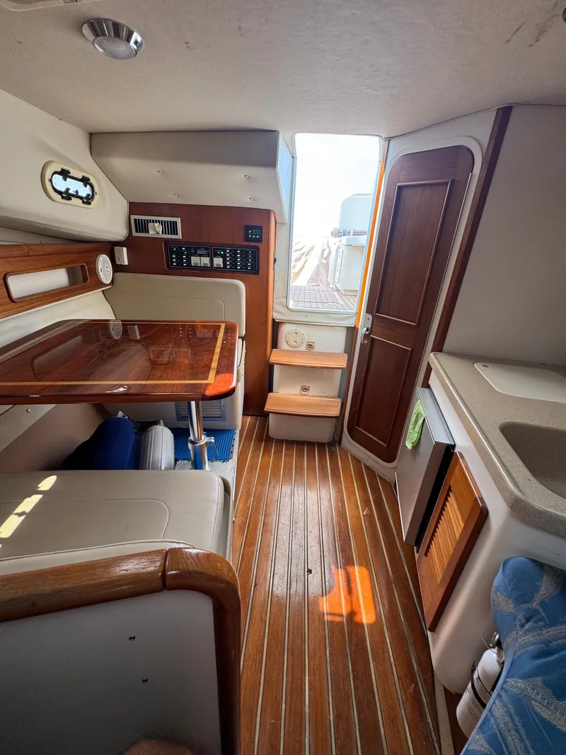 Slide: The Image of Interior of a 2002 Pursuit 3000 Express with wood flooring, table, and kitchenette. - 25