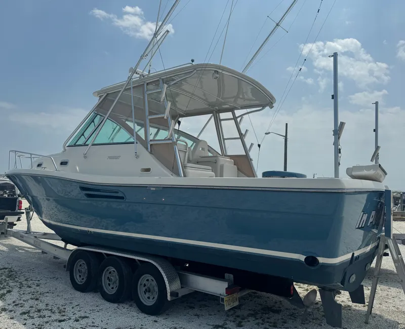 Slide: The Image of A 2002 Pursuit 3000 Express boat on a trailer. It features a blue hull. - 3