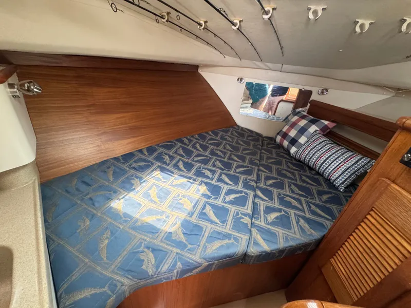 Slide: The Image of The cabin of the 2002 Pursuit 3000 Express features a cozy bed with blue bedding. - 28