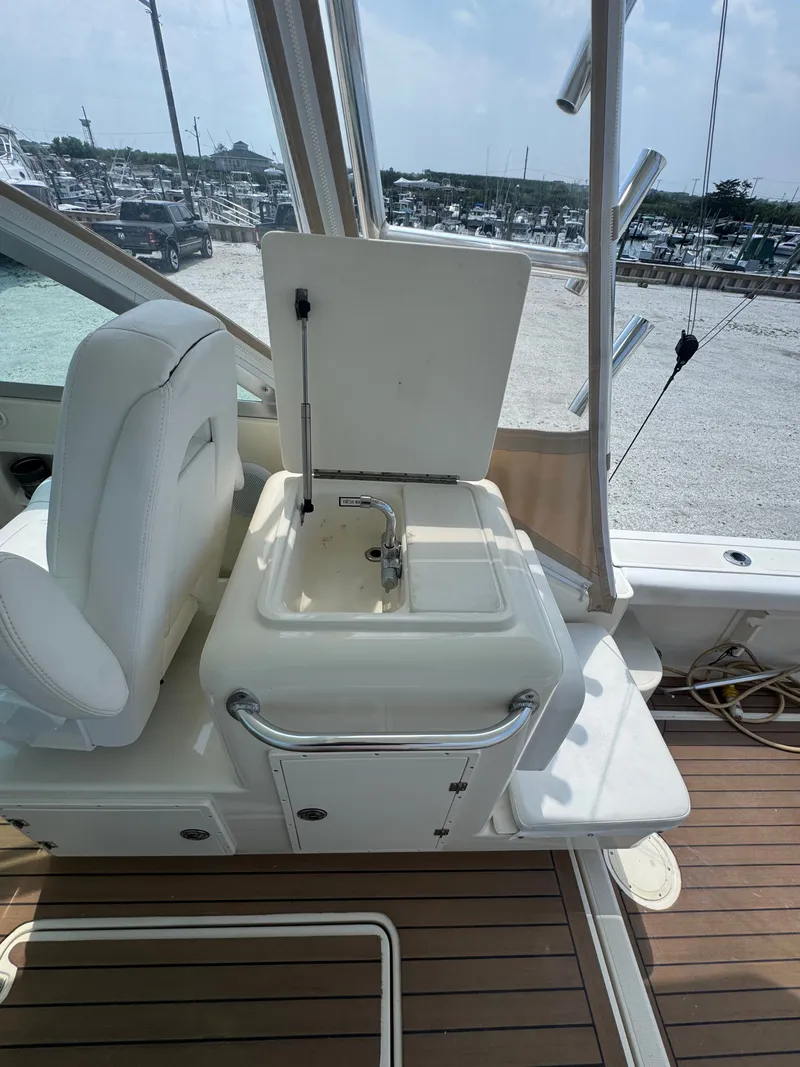 Slide: The Image of A sink on a boat with a white seat and wooden deck, parked at a marina. - 19