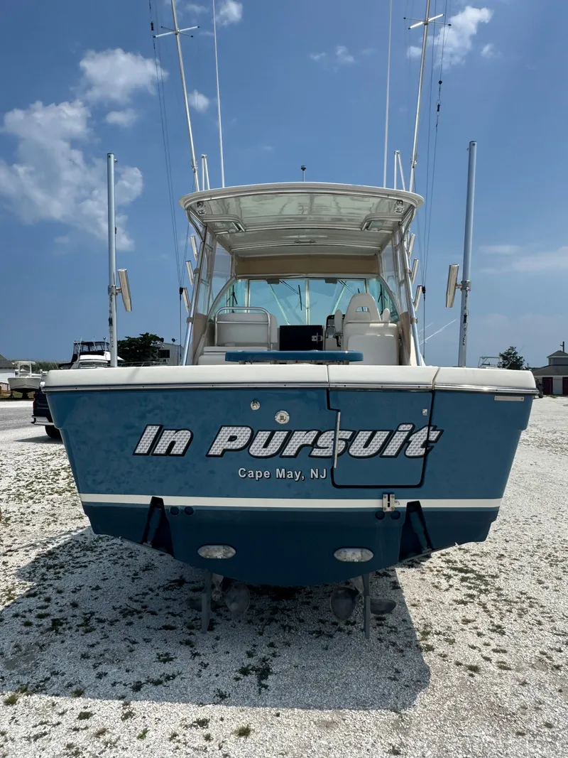 Slide: The Image of A blue boat named "In Pursuit" is on a gravel lot. - 2