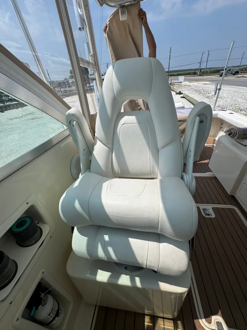 Slide: The Image of A white captain's chair on a boat with wooden flooring and clear outdoor view. - 21