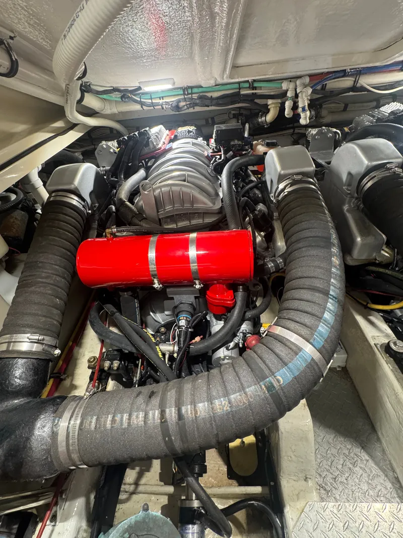 Slide: The Image of Engine room of a 2002 Pursuit 3000 Express with visible hoses and a red cylinder. - 36