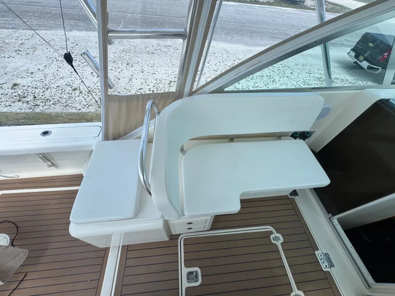Slide: The Image of The image shows the seating area of a 2002 Pursuit 3000 Express boat with wooden flooring. - 20