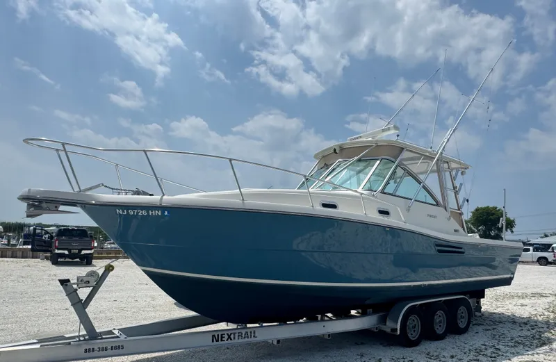 The Image of 2002 Pursuit 3000 Express on a trailer, featuring a blue hull and white superstructure. - 0