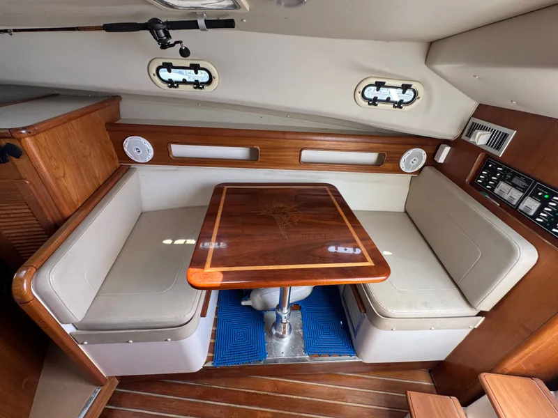 Slide: The Image of Interior of a 2002 Pursuit 3000 Express with a wooden table and cushioned benches. - 26