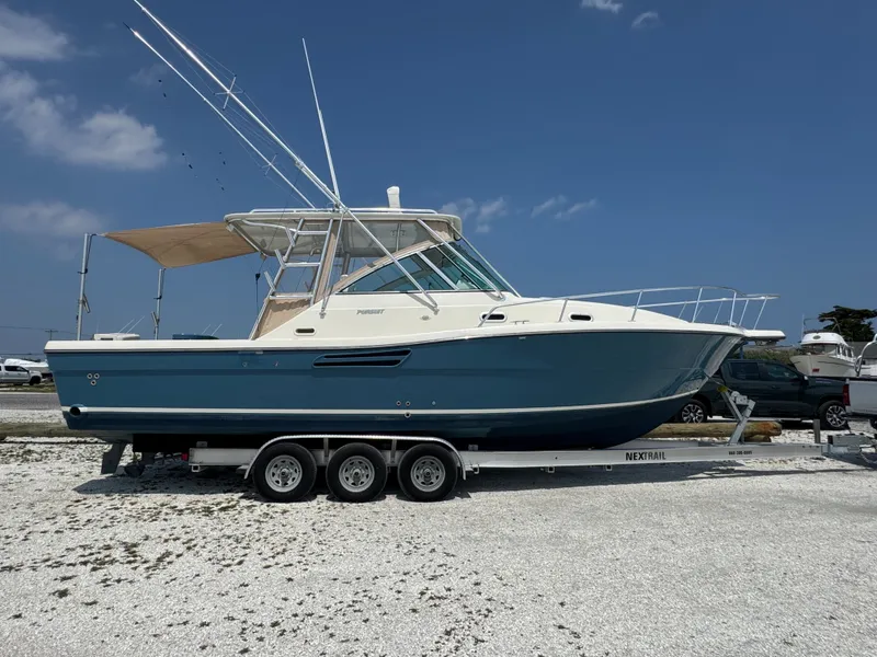 Slide: The Image of A 2002 Pursuit 3000 Express boat on a trailer in a gravel lot. - 8
