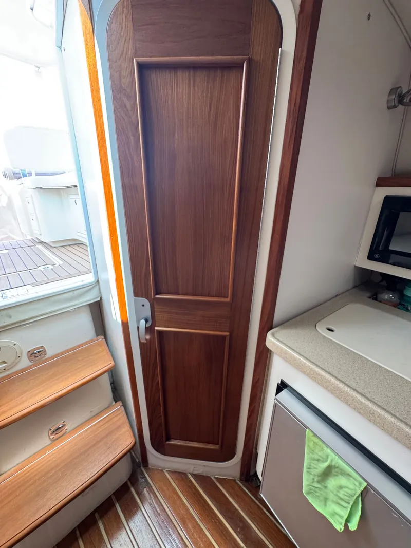 Slide: The Image of Interior of a 2002 Pursuit 3000 Express with wooden door, stairs, and kitchenette. - 30