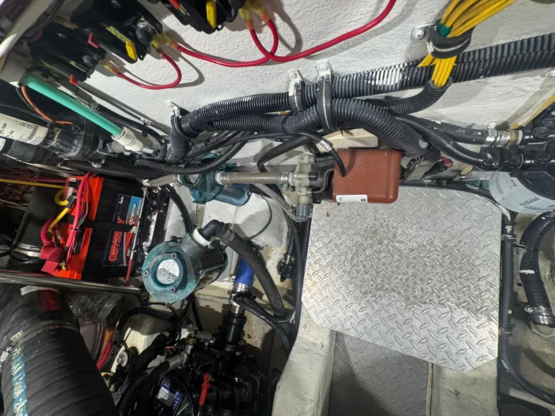 Slide: The Image of The engine room of a 2002 Pursuit 3000 Express shows cables, batteries, and mechanical components. - 38