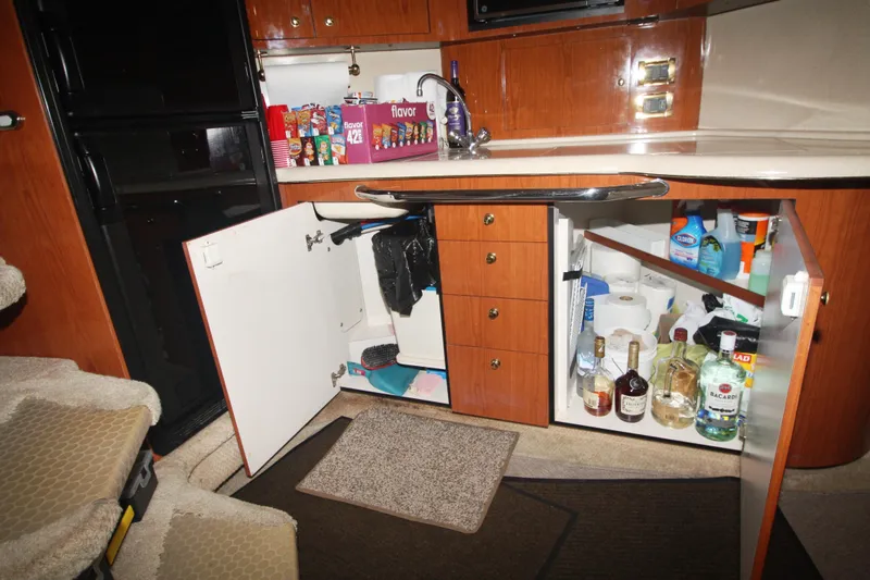 Slide: The Image of 1999 Sea Ray 380 Sundancer kitchen with open cabinets, showcasing storage and supplies. - 52