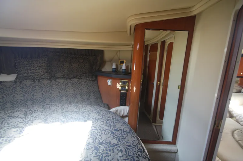 Slide: The Image of 1999 Sea Ray 380 Sundancer cabin interior with patterned bedding and wooden cabinetry. - 55