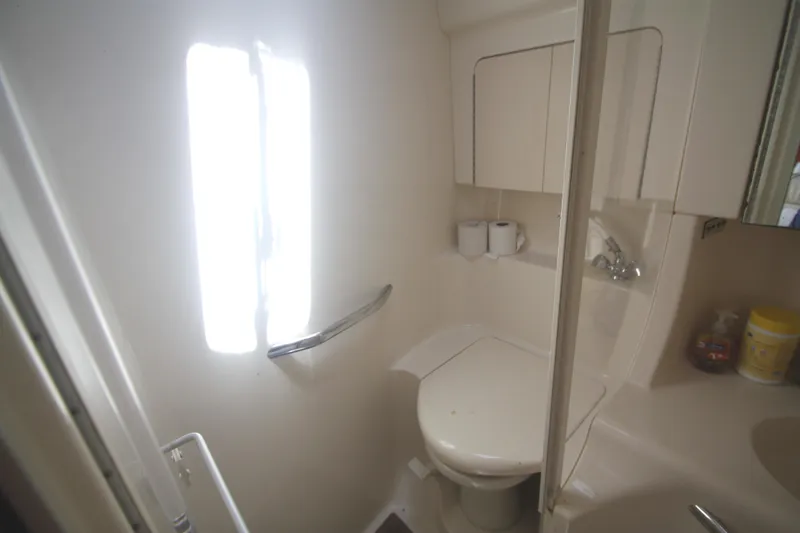 Slide: The Image of Compact bathroom in a 1999 Sea Ray 380 Sundancer yacht, featuring a toilet and sink. - 58