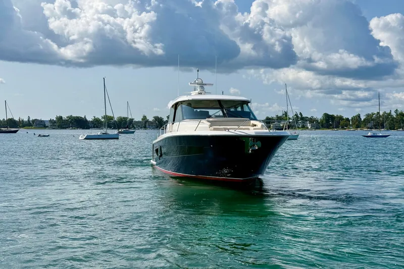Slide: The Image of 2027 Tiara Yachts EX 54 cruising on a serene lake under a cloudy sky. - 8