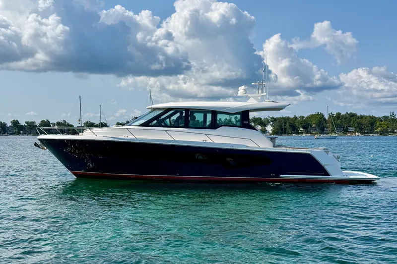 Slide: The Image of 2027 Tiara Yachts EX 54 luxury yacht on clear blue water under a partly cloudy sky. - 3