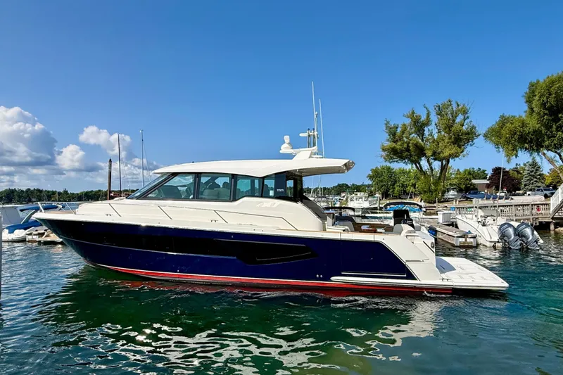 Slide: The Image of 2027 Tiara Yachts EX 54 luxury yacht docked in a scenic marina. - 2