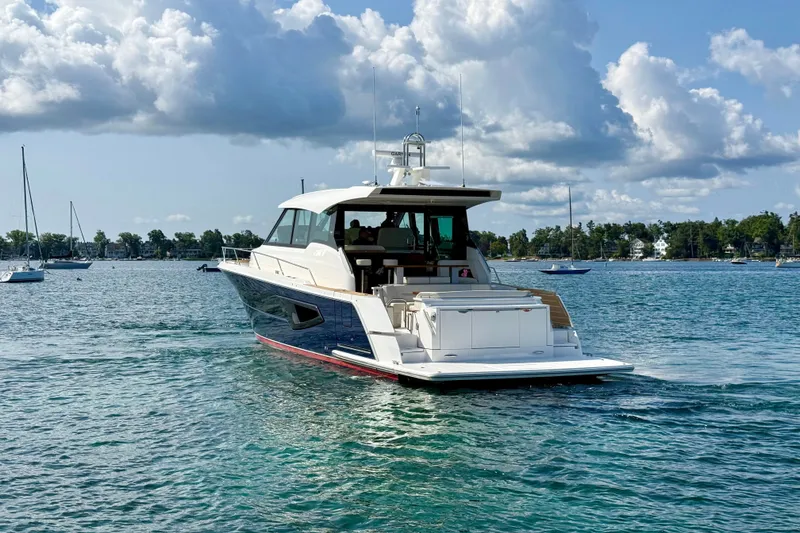 Slide: The Image of 2027 Tiara Yachts EX 54 cruising on a serene lake under a partly cloudy sky. - 4
