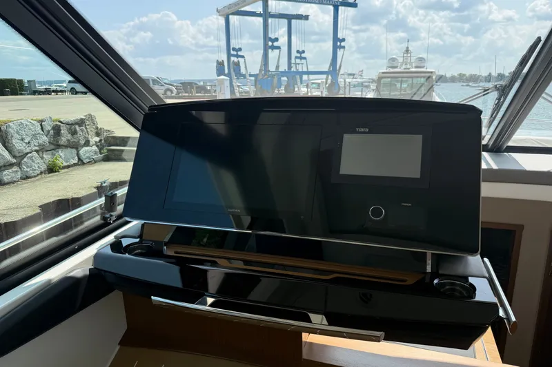 Slide: The Image of 2027 Tiara Yachts EX 54 helm with advanced navigation displays and marina view. - 24