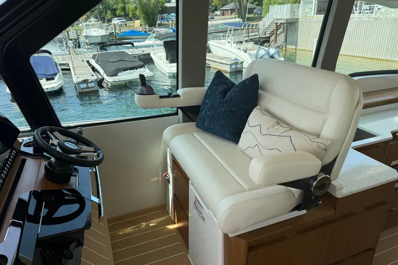 Slide: The Image of Interior helm of 2027 Tiara Yachts EX 54 with plush seating and marina view. - 15