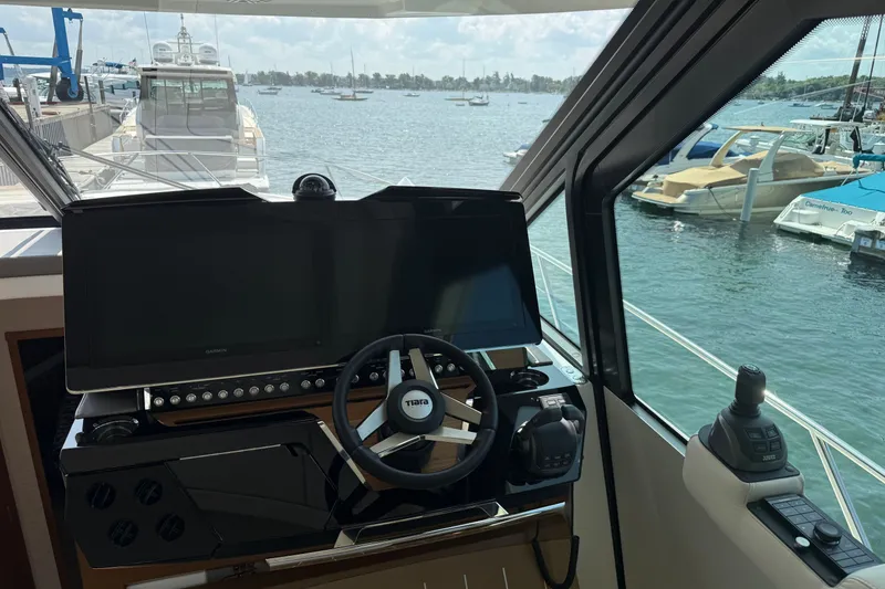 Slide: The Image of Cockpit view of 2027 Tiara Yachts EX 54, featuring modern navigation equipment and steering wheel. - 23