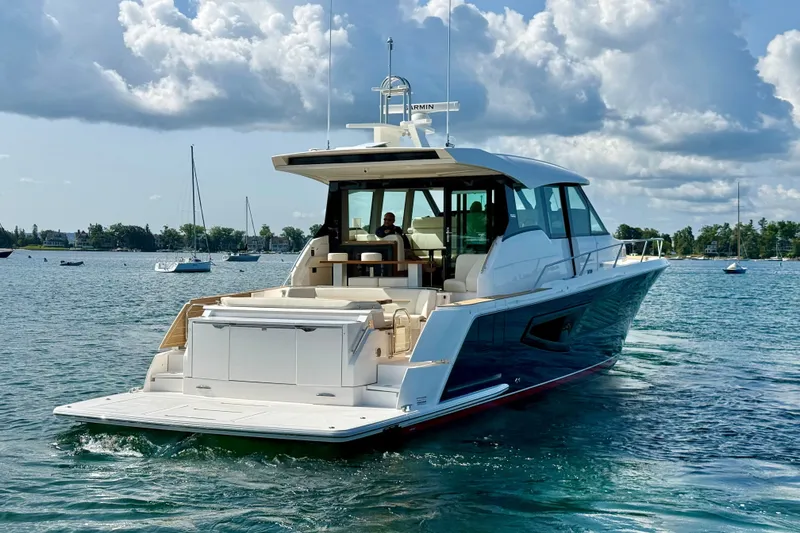 Slide: The Image of 2027 Tiara Yachts EX 54 cruising on a serene lake under a partly cloudy sky. - 6