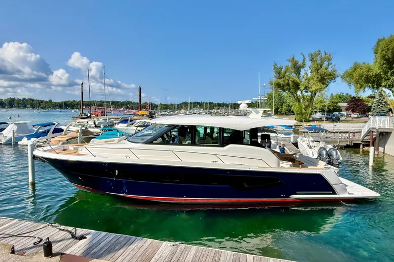 Slide: The Image of 2027 Tiara Yachts EX 54 docked in a scenic marina under a clear blue sky. - 1