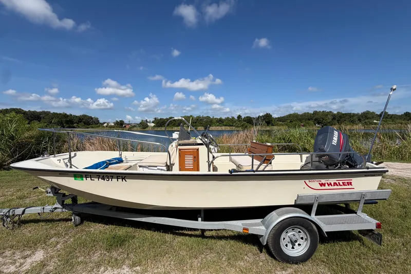 Slide: The Image of 1987 Boston Whaler 17 Montauk boat on trailer by a lake under blue sky. - 4