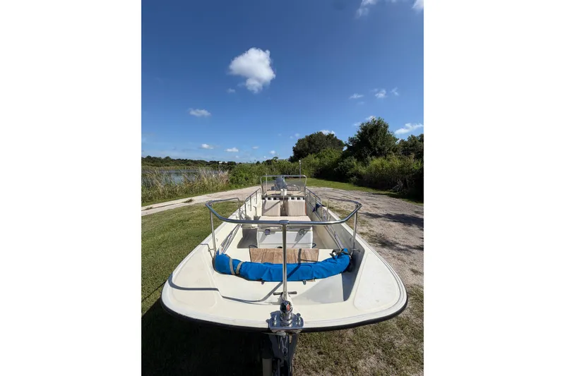 Slide: The Image of 1987 Boston Whaler 17 Montauk boat on grassy path under clear blue sky. - 1