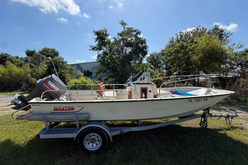 Slide: The Image of 1987 Boston Whaler 17 Montauk boat on trailer, parked outdoors under clear sky. - 3