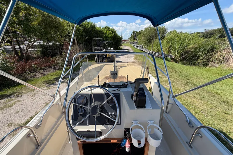 Slide: The Image of 1987 Boston Whaler 17 Montauk boat interior with steering wheel and blue canopy. - 11