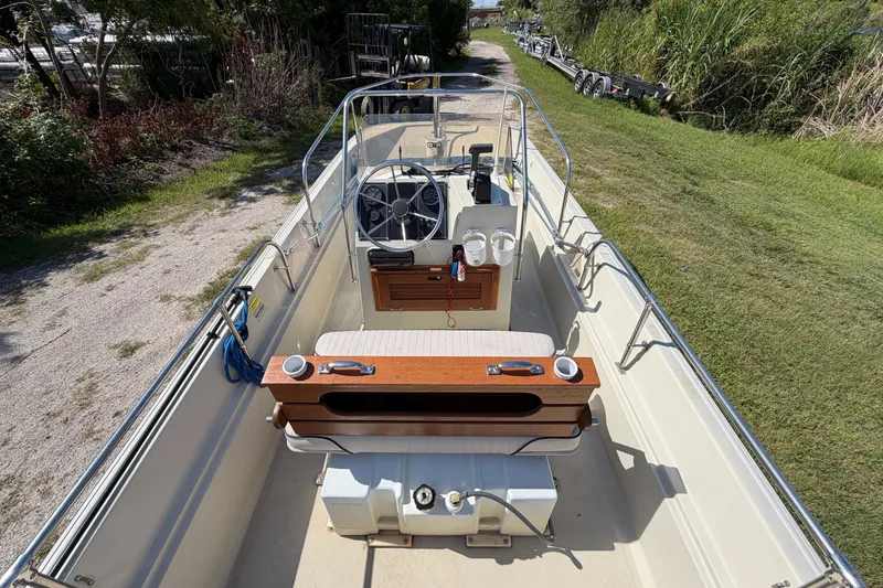 Slide: The Image of 1987 Boston Whaler 17 Montauk boat interior with steering wheel and seating, parked on grass. - 9