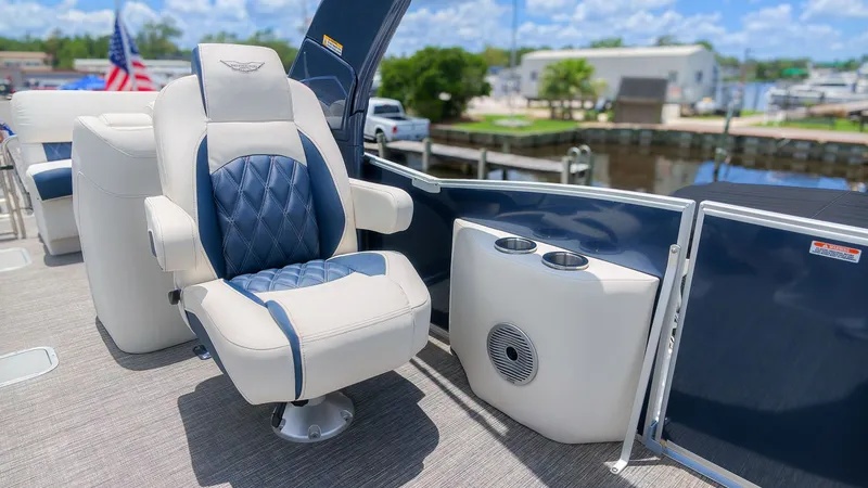 Slide: The Image of A luxurious seat on a Bennington 25 QFBA boat, featuring blue upholstery and cup holders. - 15