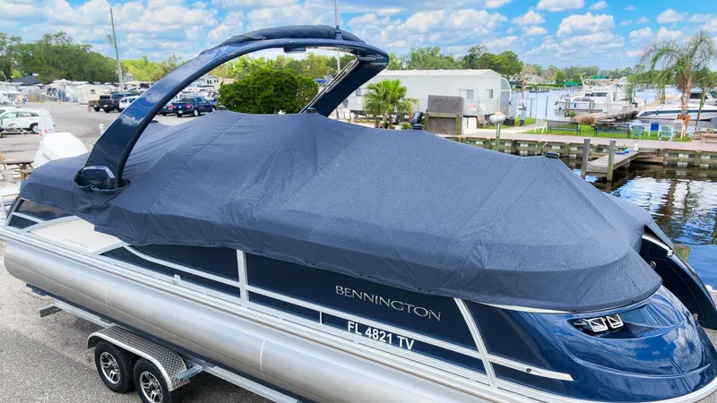 Slide: The Image of A 2024 Bennington 25 QFBA pontoon boat with a blue cover on a trailer. - 4