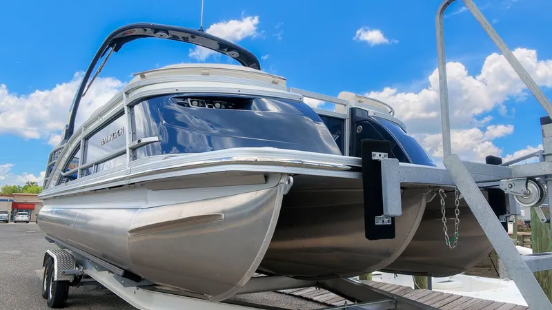 Slide: The Image of A Bennington 25 QFBA pontoon boat on a trailer under a blue sky. - 4