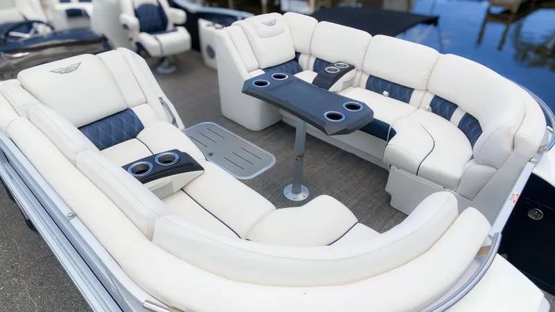 Slide: The Image of Luxurious white seating area on a Bennington 25 QFBA pontoon boat, featuring blue accents and cup holders. - 14