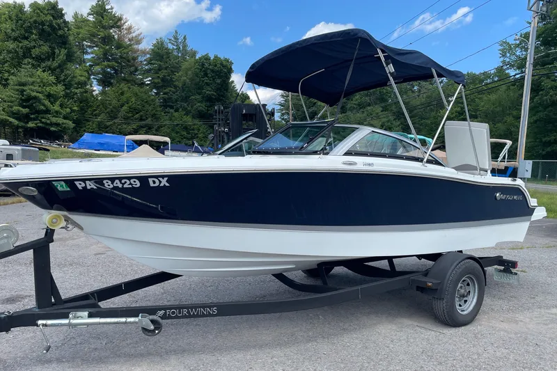 Slide: The Image of 2020 Four Winns H190 boat on trailer, parked outdoors with trees in background. - 17
