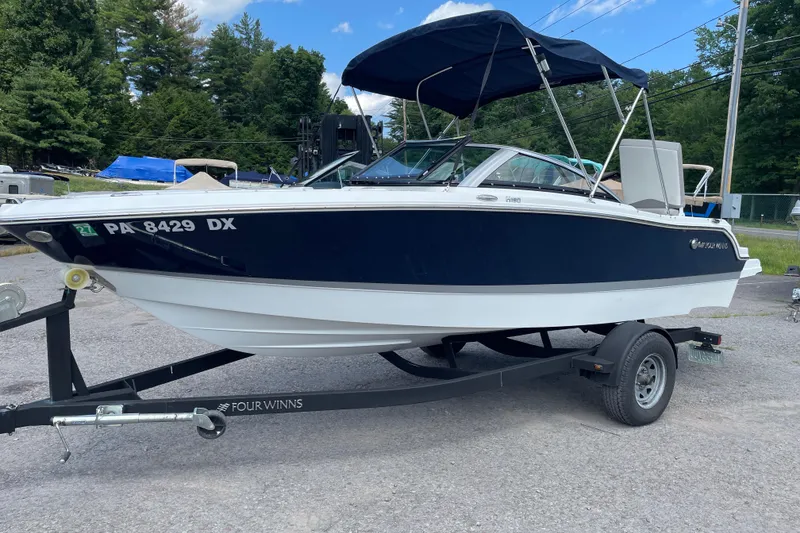 Slide: The Image of 2020 Four Winns H190 boat on trailer with canopy, parked outdoors. - 2