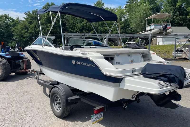 Slide: The Image of 2020 Four Winns H190 boat on trailer, parked outdoors with trees in background. - 18