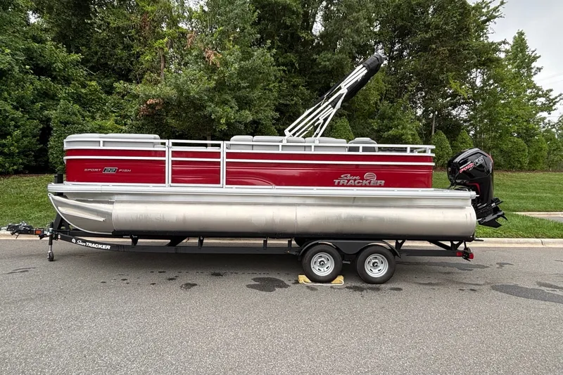 The Image of 2026 Sun Tracker SportFish 22 DLX pontoon boat on trailer, parked on road. - 0