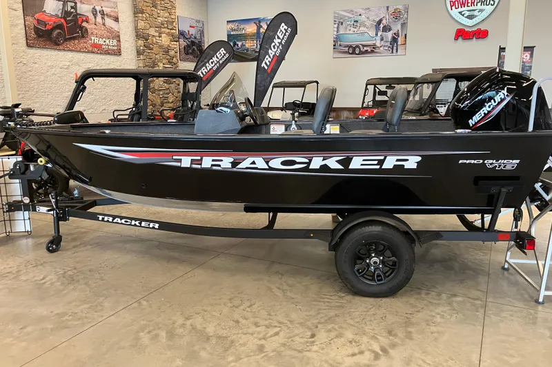 The Image of 2026 Tracker Pro Guide V-16 SC boat displayed in showroom with promotional banners. - 0
